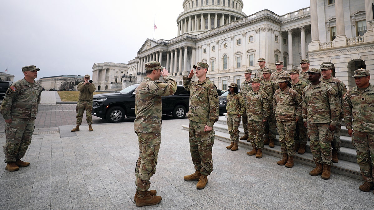 National Guard members salute in front of U.S. Capitol