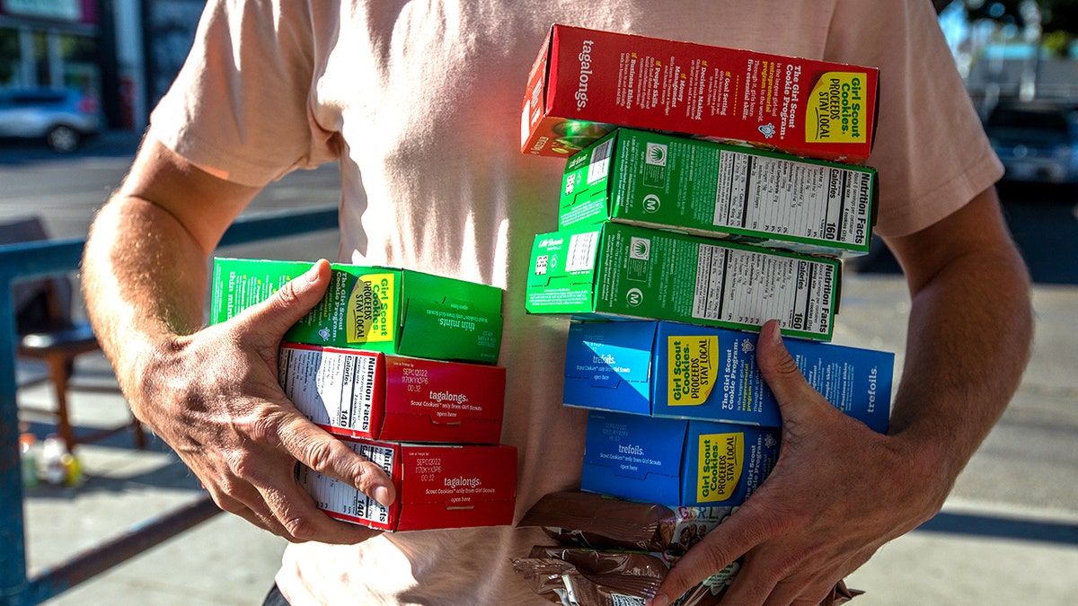 Man holding boxes of Girl Scout cookies