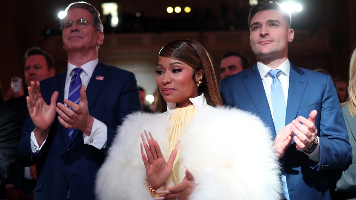 Nicki Minaj claps while attending the Trump Accounts Summit while seated in the Andrew W. Mellon Auditorium.