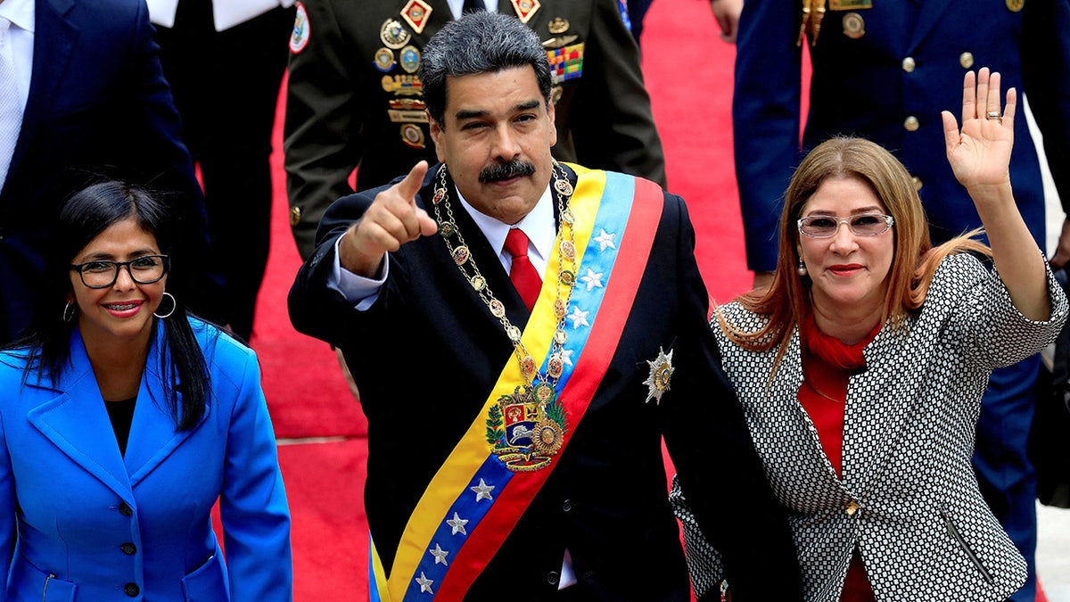 Venezuela's President Nicolás Maduro points finger as he stands near Cilia Flores and Delcy Rodriguez