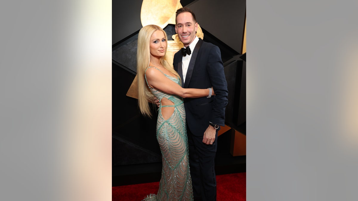 Paris Hilton holding onto her husband in a seagreen lace dress.