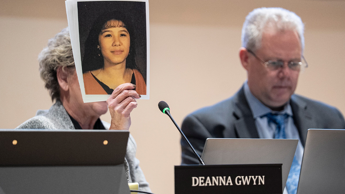 A person holds up a printed photograph during a Salem City Council meeting