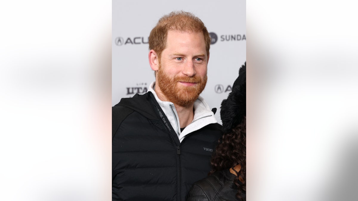 Primer plano del príncipe Harry una chaqueta oscura y una camisa blanca con cuello.