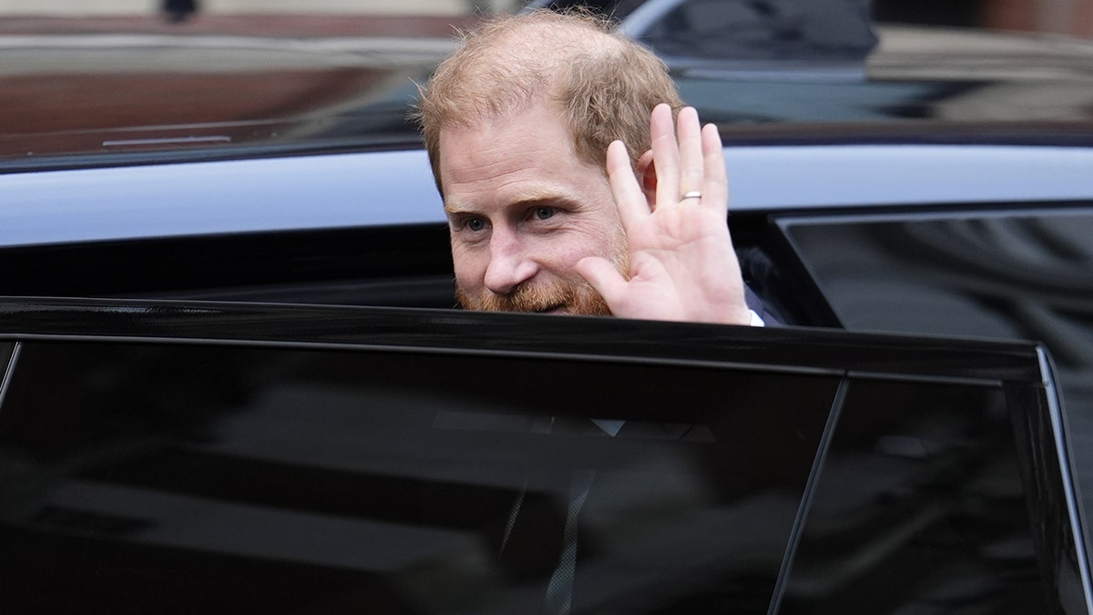 Prince Harry waving from a car.