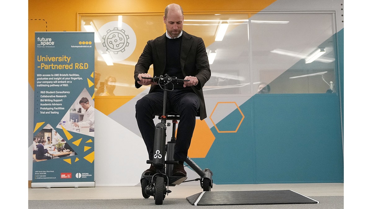 El príncipe William un scooter ligero para personas con movilidad reducida dentro de un laboratorio.