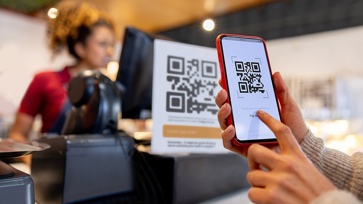 A woman scanning a QR code on her phone for mobile payment