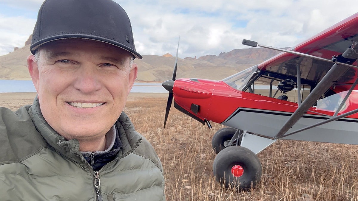 Roland Steadham smiling in a selfie photo next to a red aircraft.