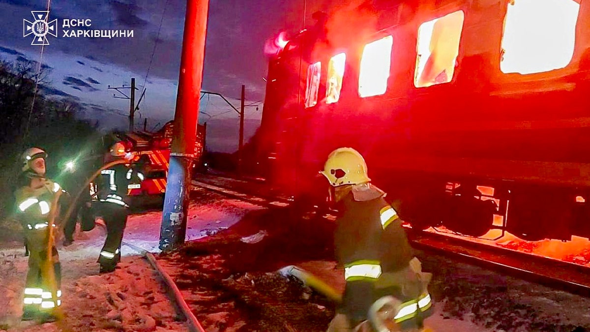Firefighters extinguish flames around damaged rail cars following an aerial strike.