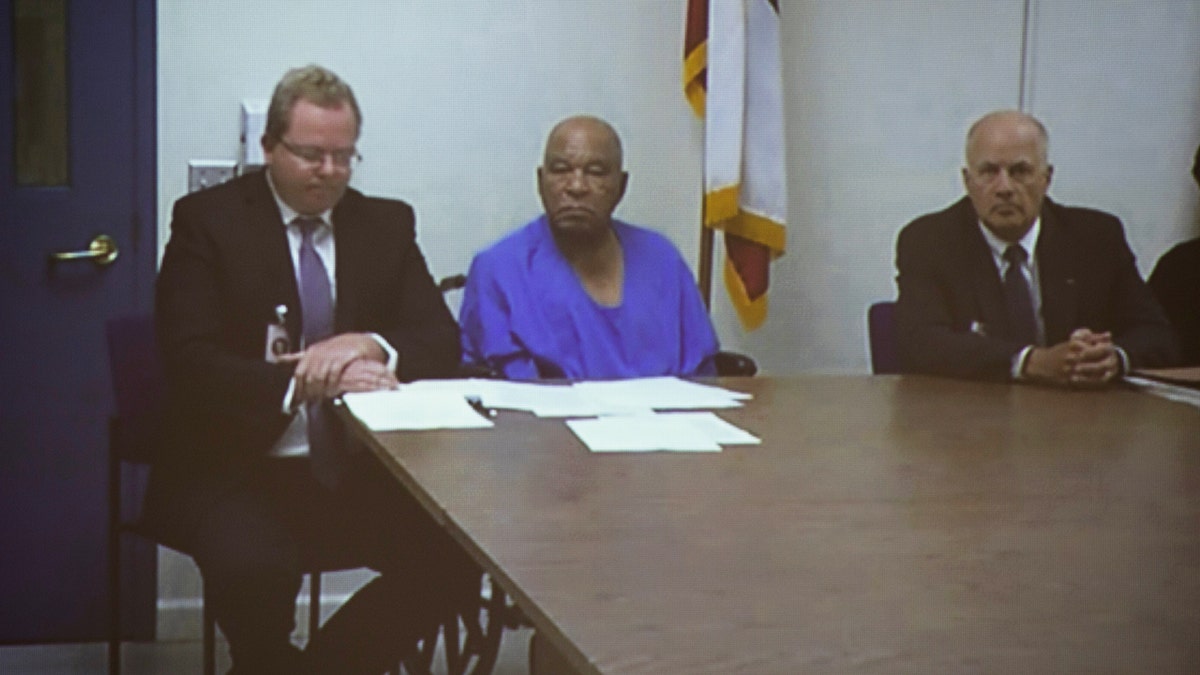 Samuel Little sentado entre abogados escuchando un juicio.