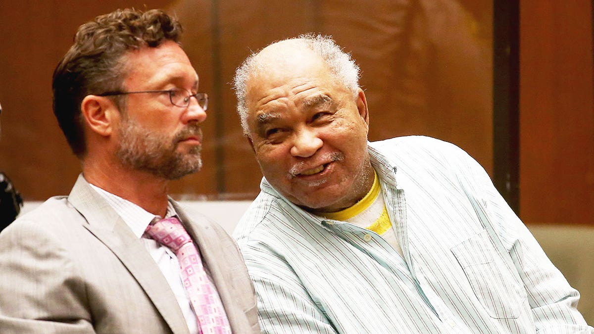 Samuel Little sonriendo burlonamente al defensor público Michael en el tribunal.