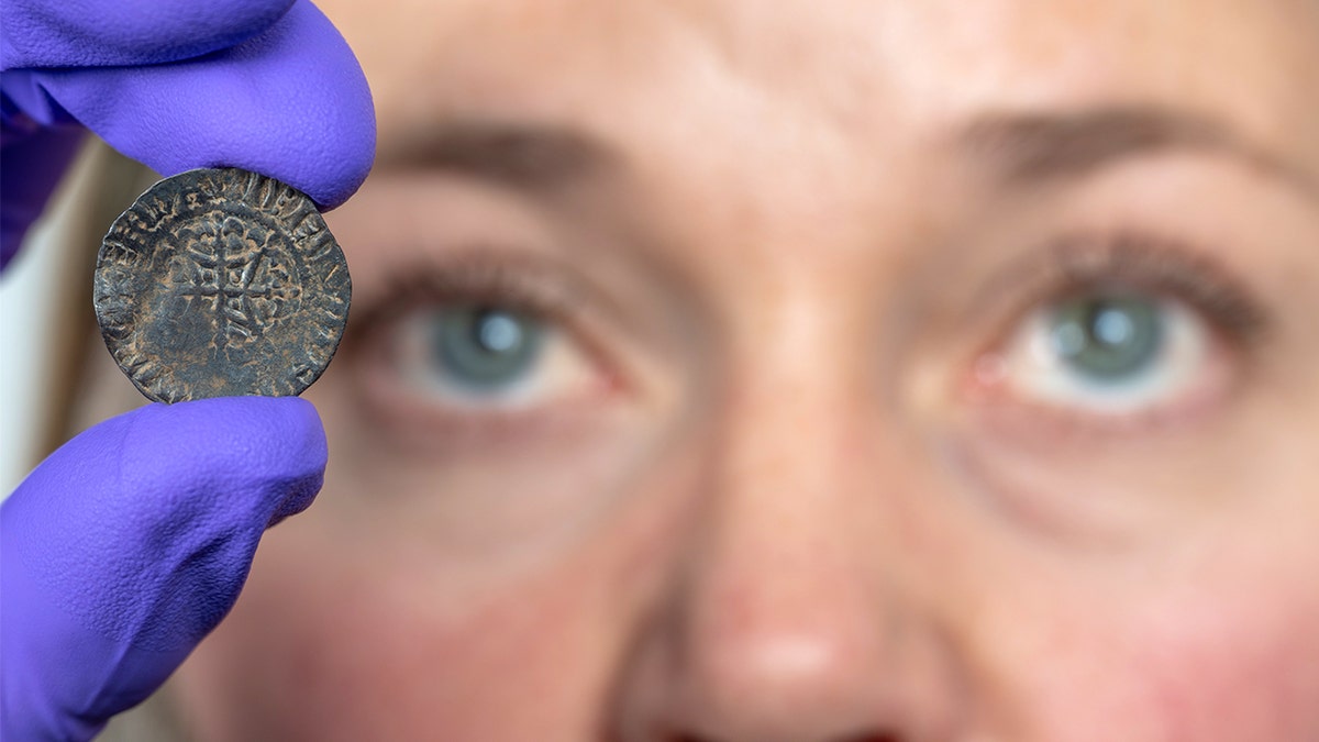 Woman holding coin near her eye