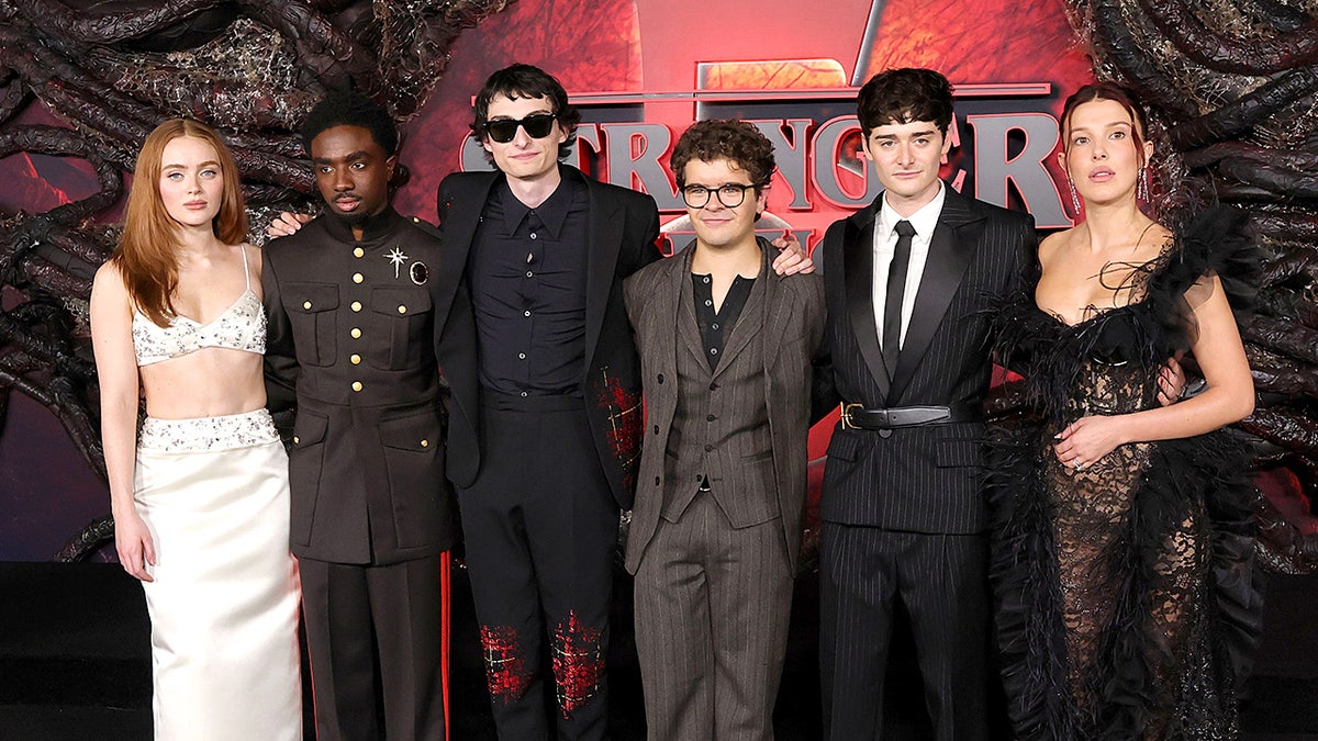 The main cast of "Stranger Things" stands together on the red carpet at a season premiere event.