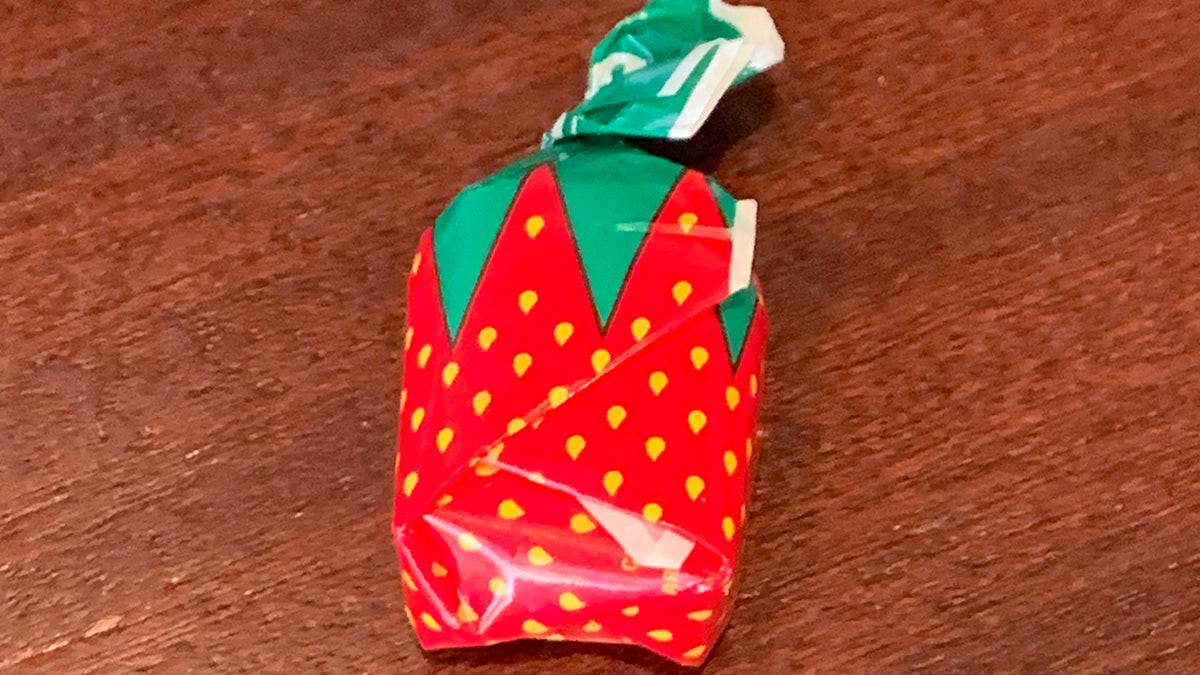 Single strawberry bonbon candy wrapped on table.