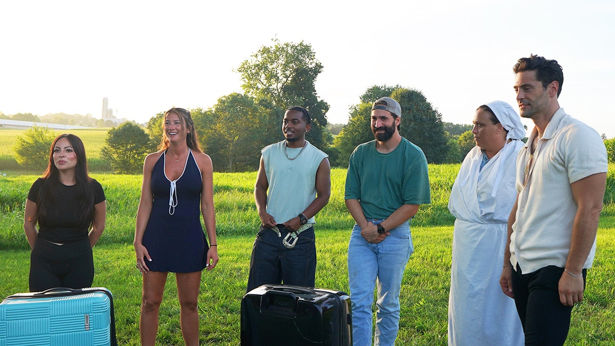 The cast of "Suddenly Amish" standing together outdoors in front of suitcases.