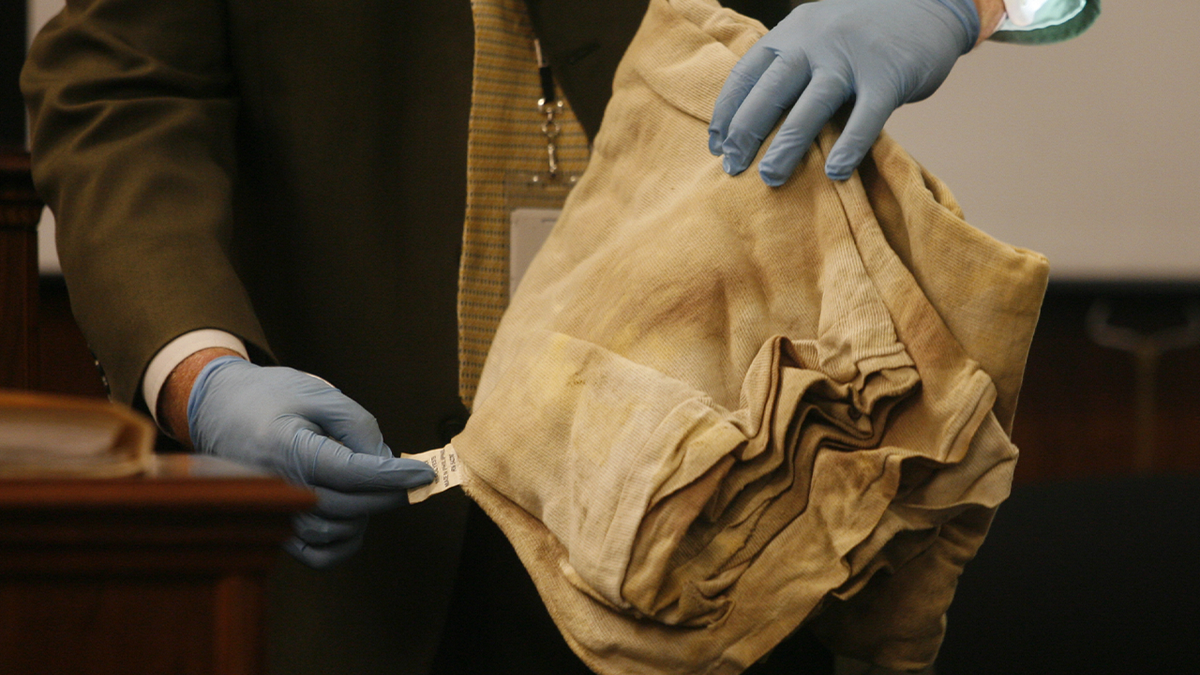 Investigators display blanket recovered as evidence during a homicide trial.