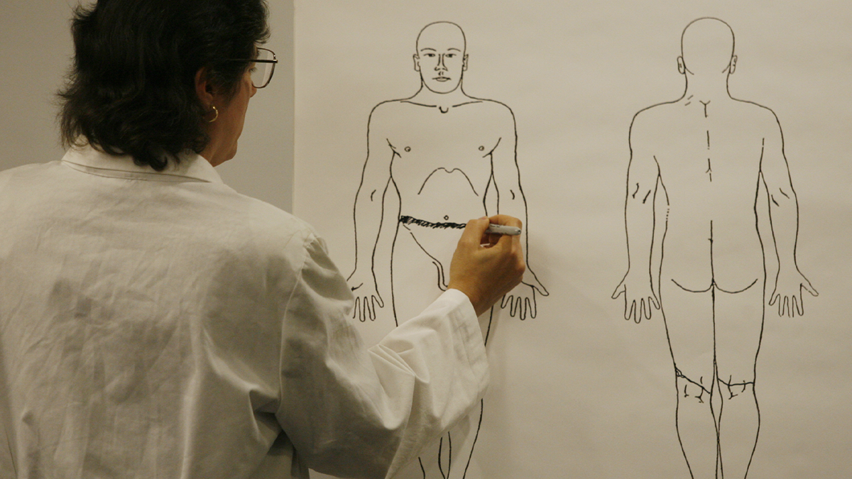 A forensic examiner marks a diagram of a human body