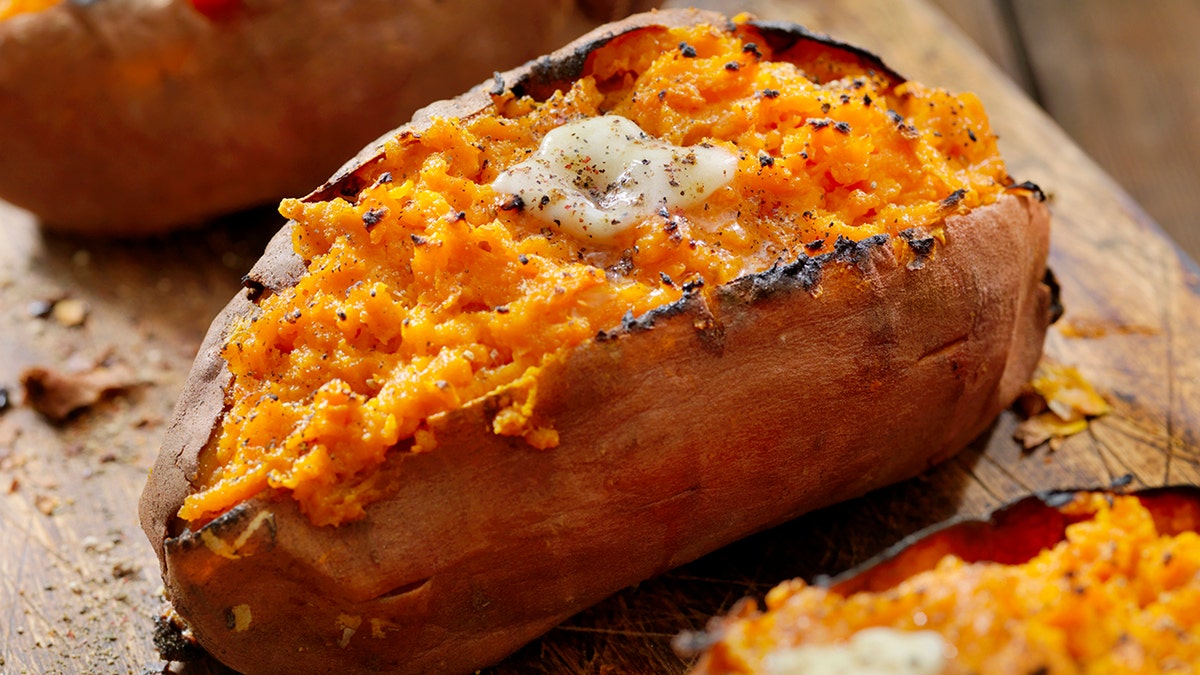 Twice baked, stuffed sweet potatoes and served on a cutting board with melted butter and chopped pepper.