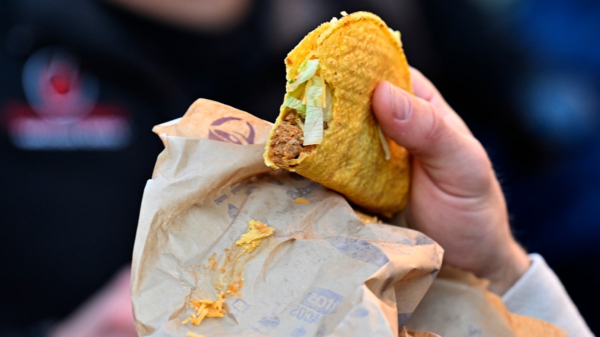 Person holding hard-shelled Taco Bell taco during 50K race.