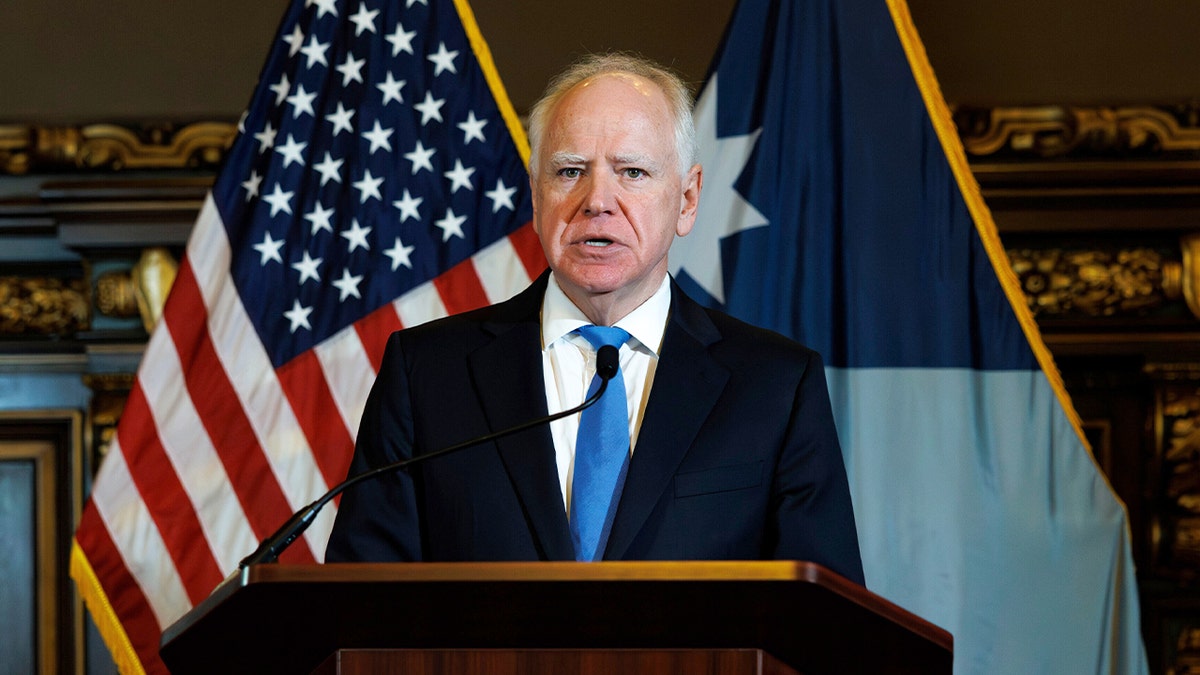 The Minnesota governor stands at a podium addressing reporters inside the state capitol.