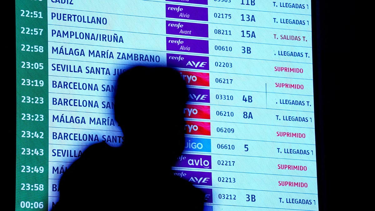A person walks past an information board amid train disaster