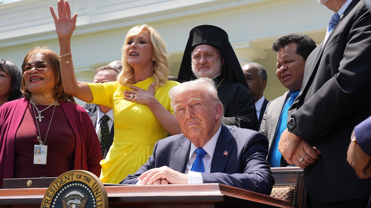 President Donald Trump sits as Head of the White House Faith Office Paula White sings 