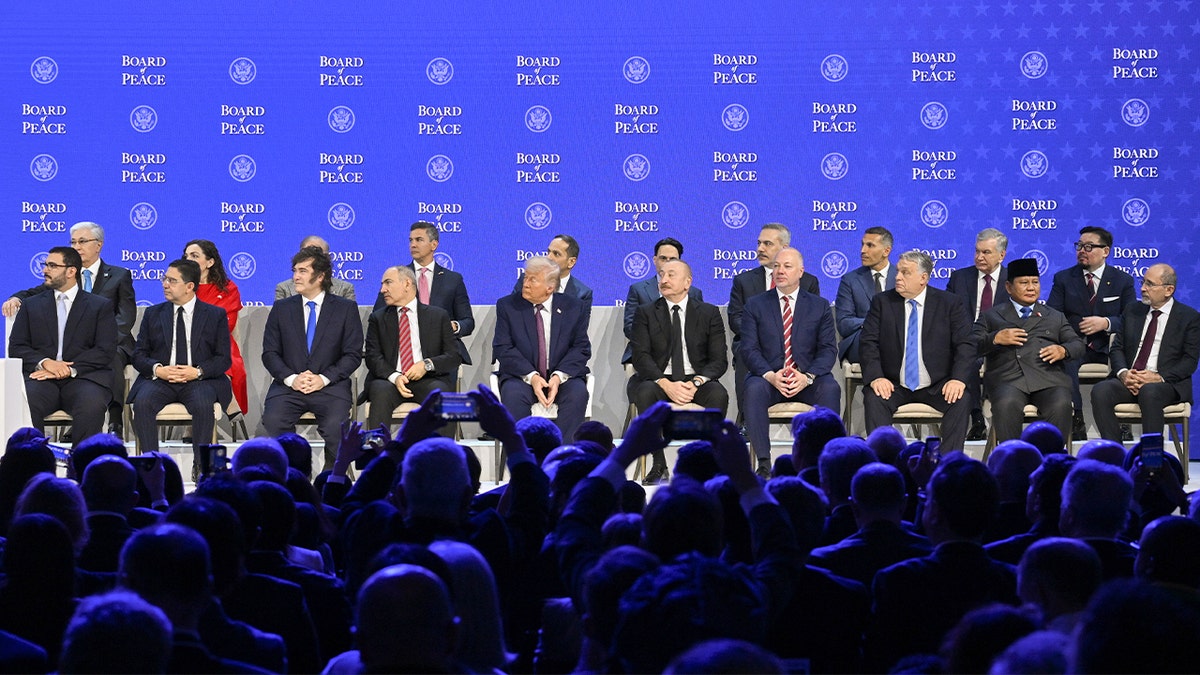 Os líderes mundiais sentam-se juntos num palco durante um evento diplomático formal numa cimeira internacional.