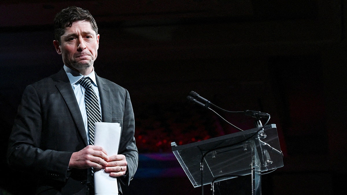 Minneapolis Mayor Jacob Frey holds papers next to a podium