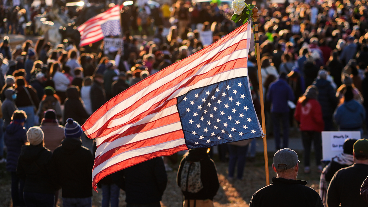 A man holds an upside down American flag.