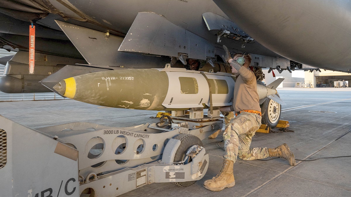 U.S. Airman attaches a GBU-31 munitions strategy   to an F-15E Strike Eagle