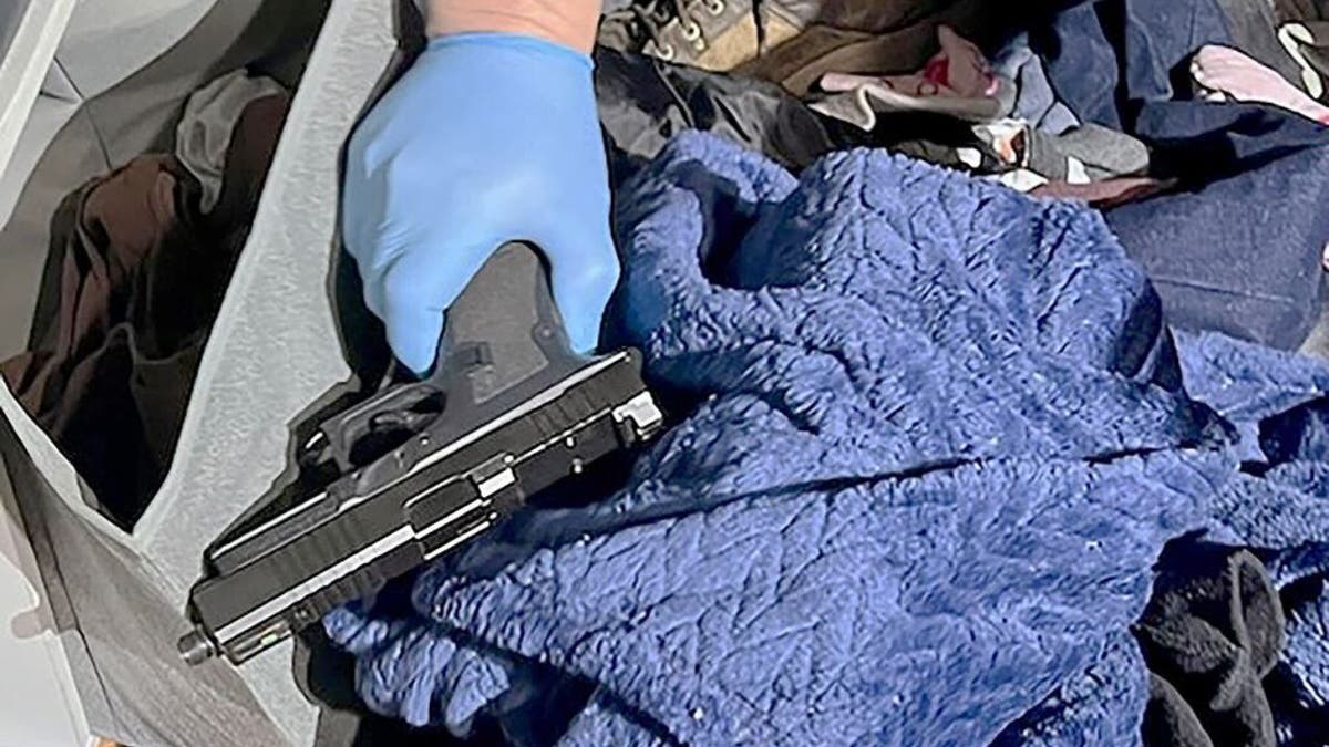 Law enforcement officer holding a handgun recovered during a fugitive arrest in Spokane, Washington.