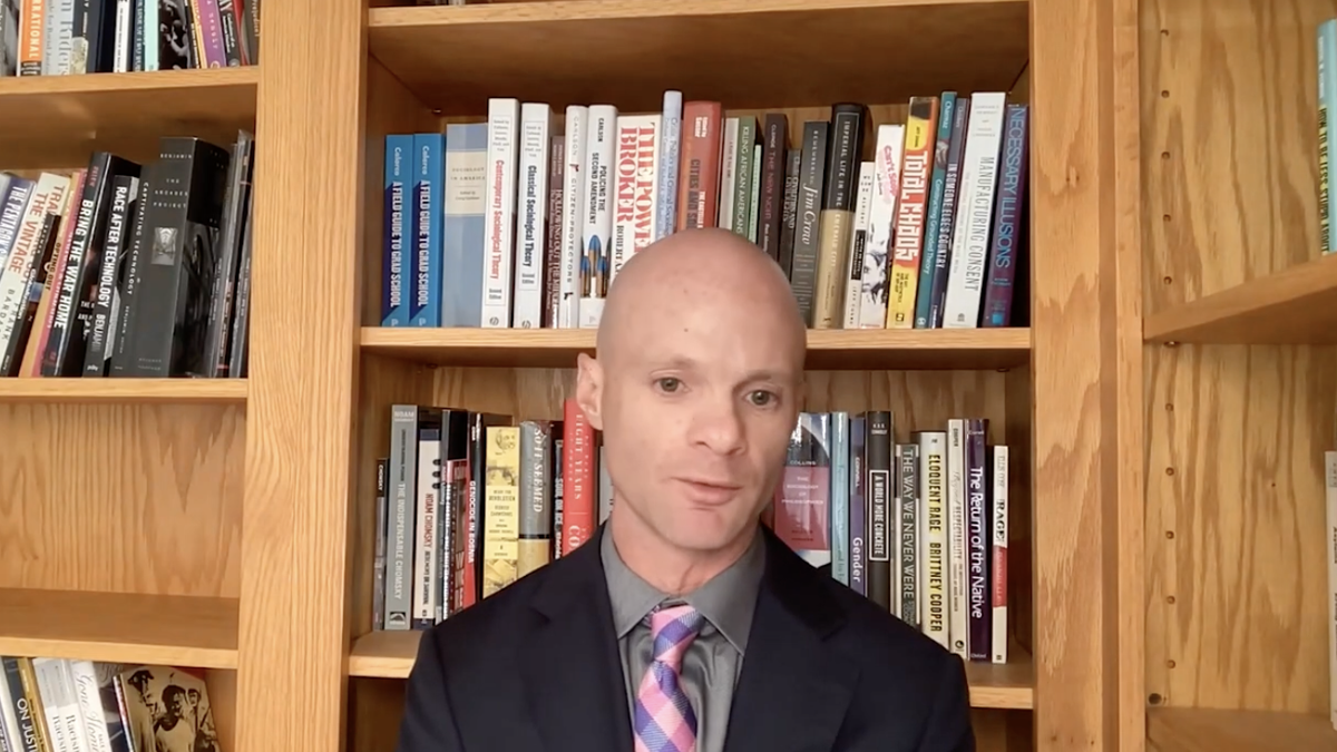 University of Iowa professor speaking online in front of book case