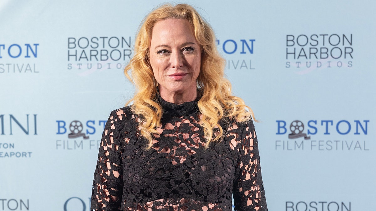 Virginia Madsen wearing a black lace dress.