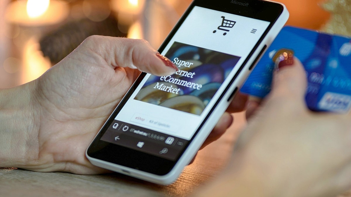 Una persona sosteniendo un teléfono mientras compra por Internet.