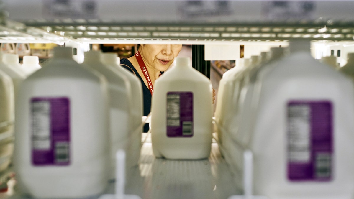 woman in fridge grabbing milk at wegmans