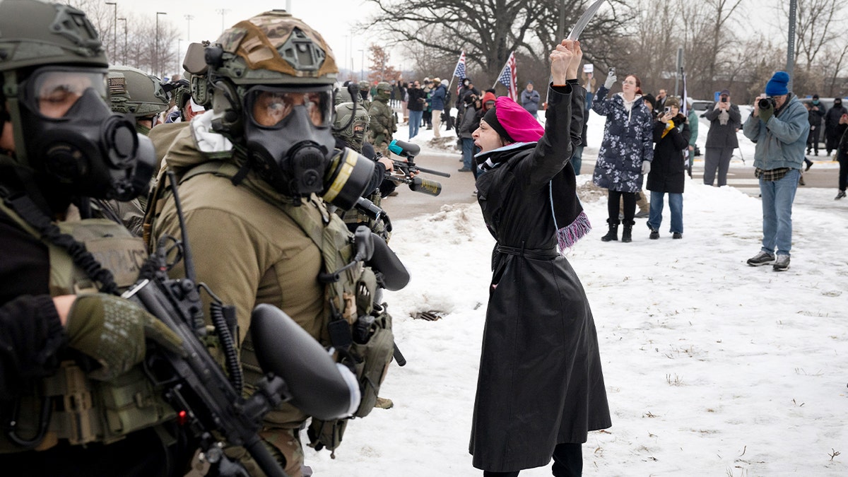 Protesters argue with law enforcement officers gathered near a secured government building.