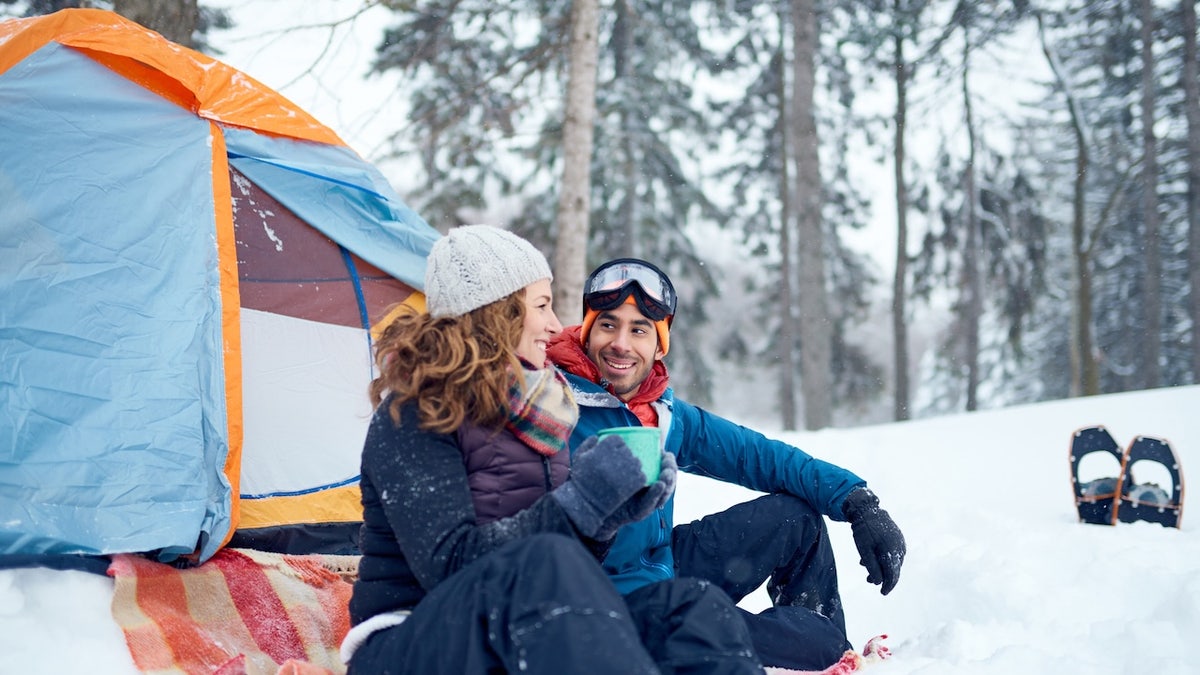 couple setting up tent and camping in the snow