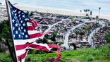 A tattered U.S. flag waves in the wind above the Pacific Palisades in California on Wednesday, Dec. 31, 2025.