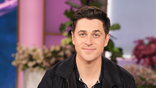 Actor David Henrie sitting with purple background
