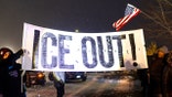 minneapolis protestors at night with ICE OUT sign