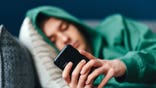 A teenage boy lies on the couch texting a message