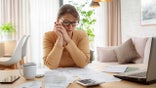 Mature woman contempling bills and tax papers at home