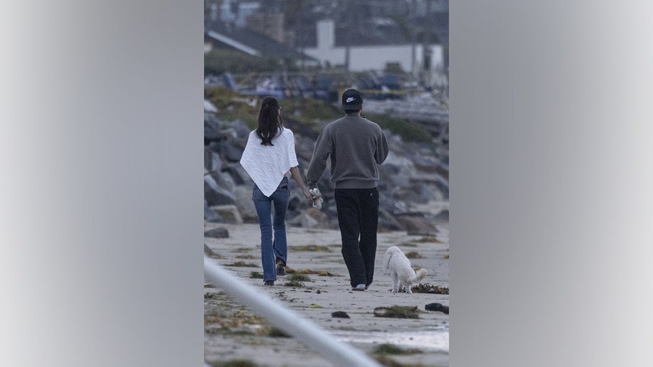 Brooklyn and Nicola hold hands on the beach.