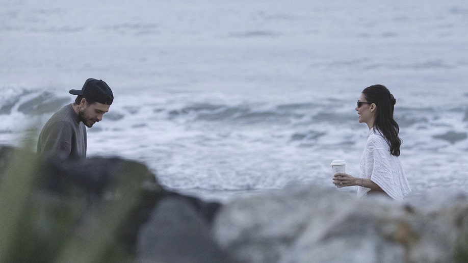 Brookly and Nicola Beckham are photographed behind grenery.