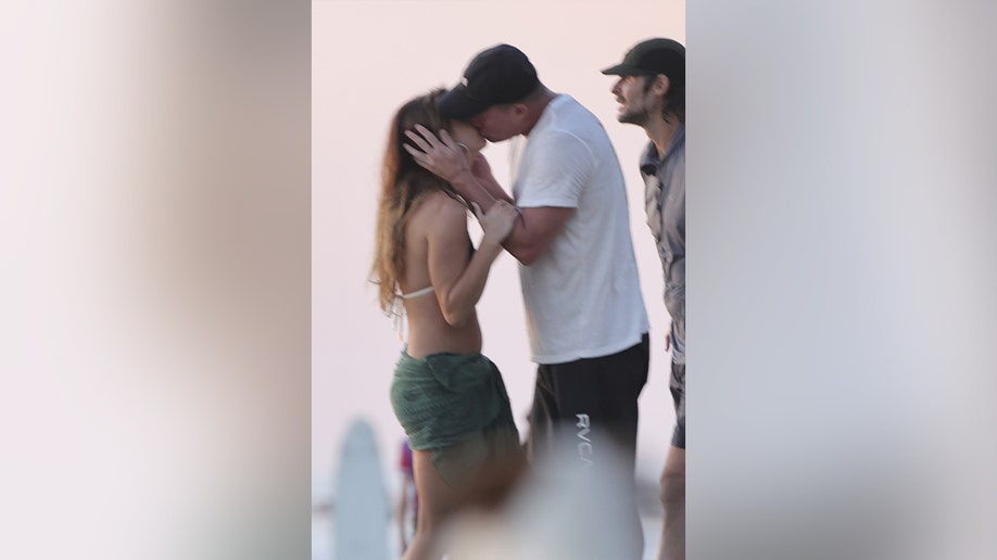 Tatum puts his hands on his girlfriends cheeks as they kiss on the beach.