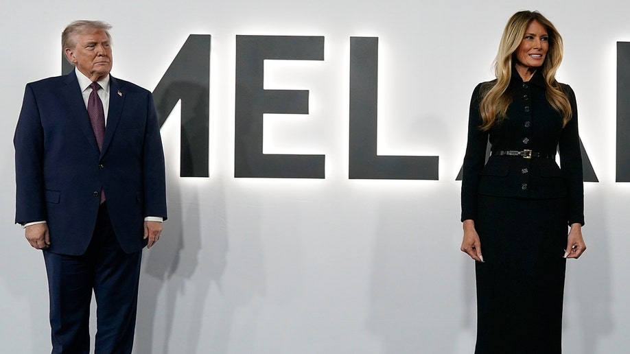 Donald Trump and Melania Trump arriving on a black carpet for a movie premiere.