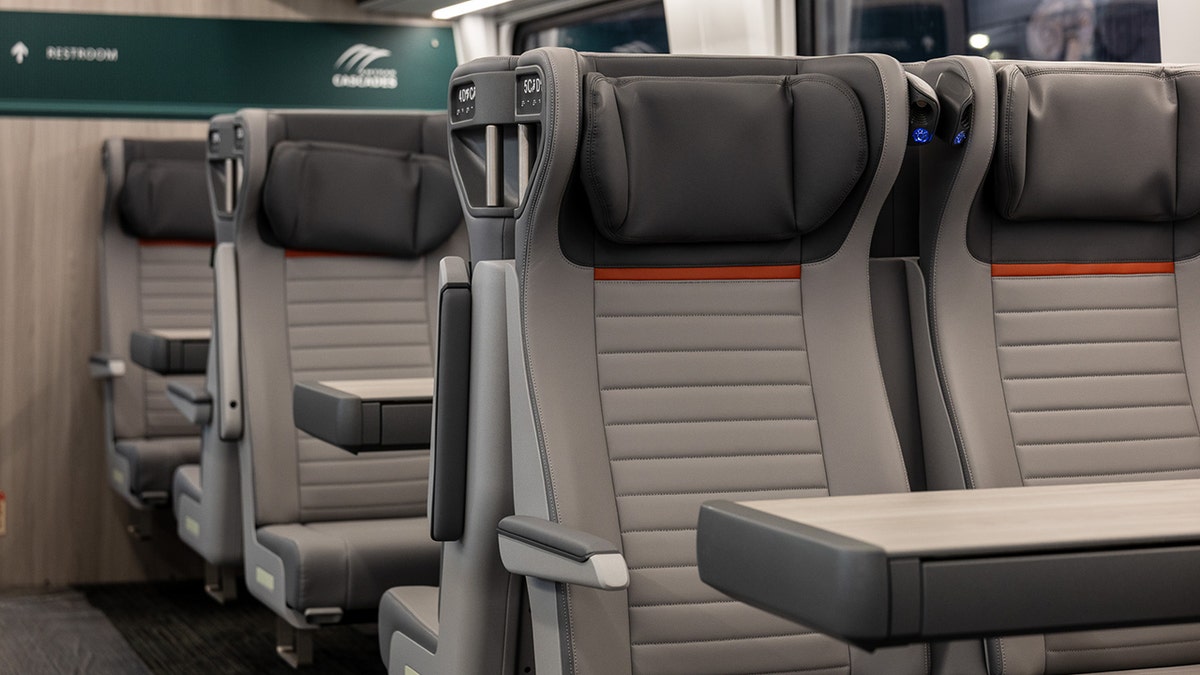 Inside of new Airo trains from Amtrak, showing food trays and cushioned seats.
