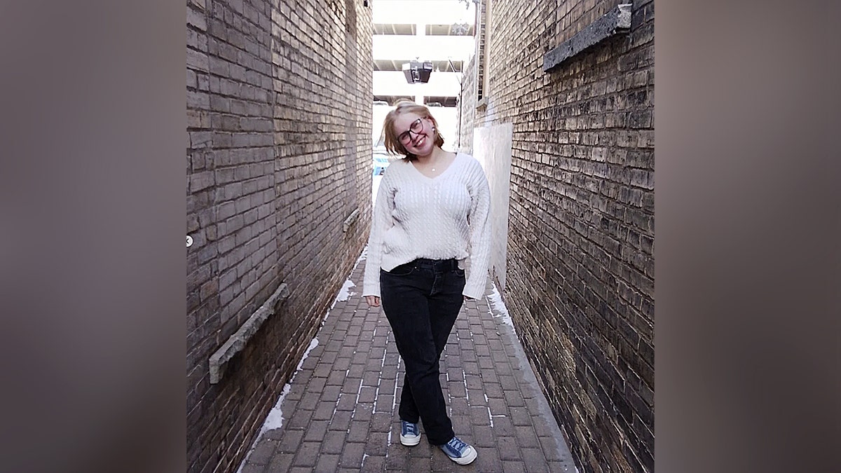 young blonde woman smiles for camera in alley photograph