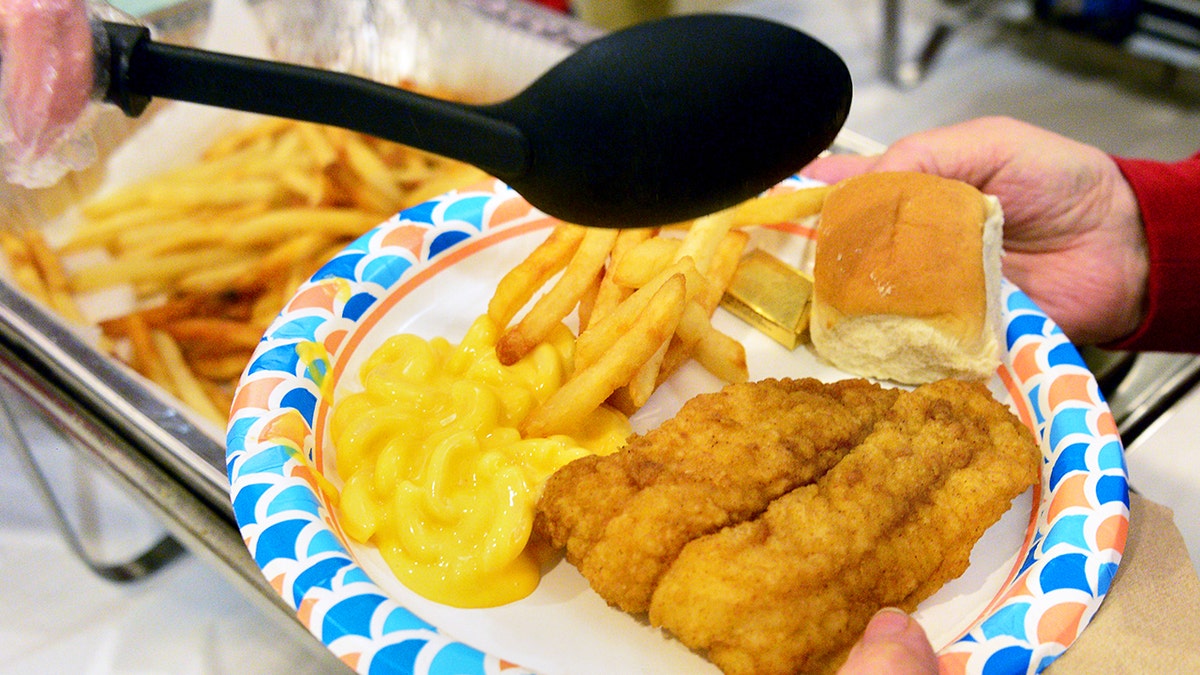 A plate of fried fish, a roll and french fries is shown.