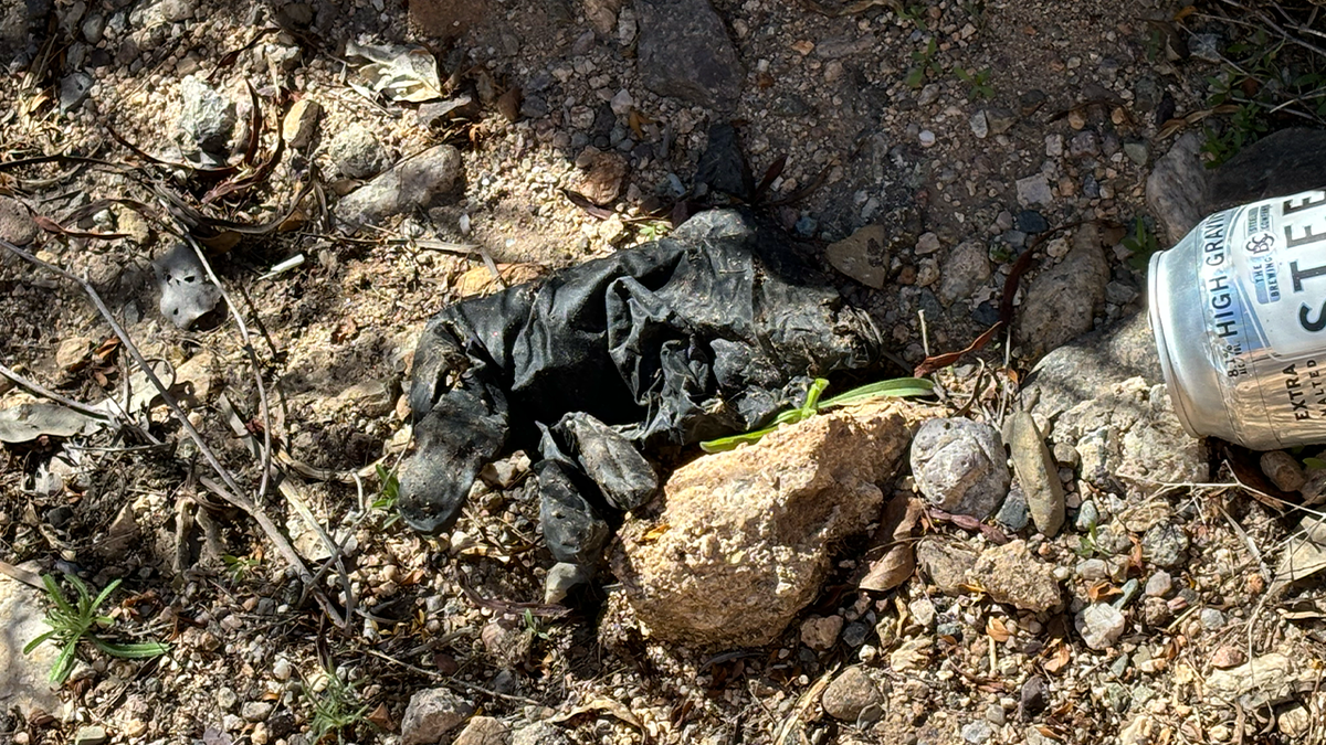 A glove on the ground near a beer can.