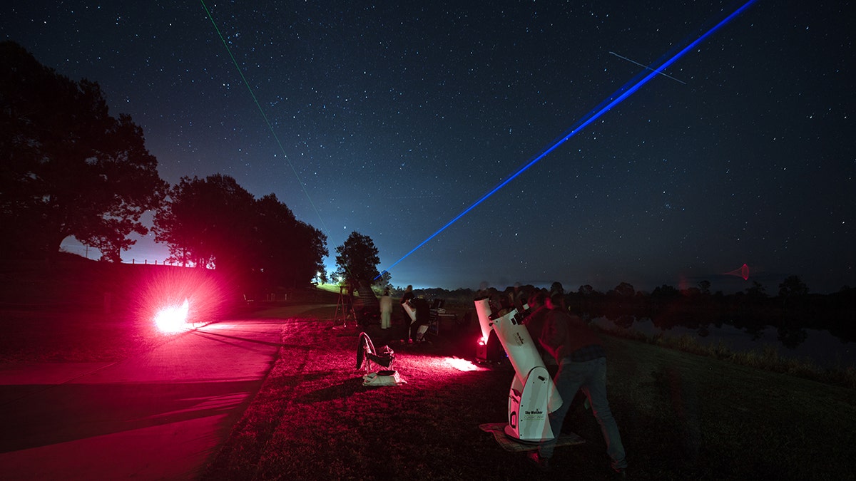 Observers shine a blue laser pointer into the sky.